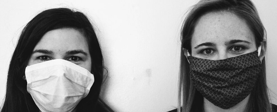 Two women wearing face masks, photographed in black and white